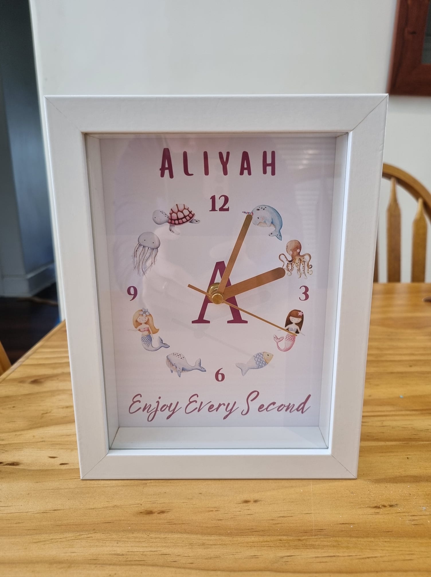 Personalised clock for children with a mermaid, turtle, octopus and fish in it sitting on the table